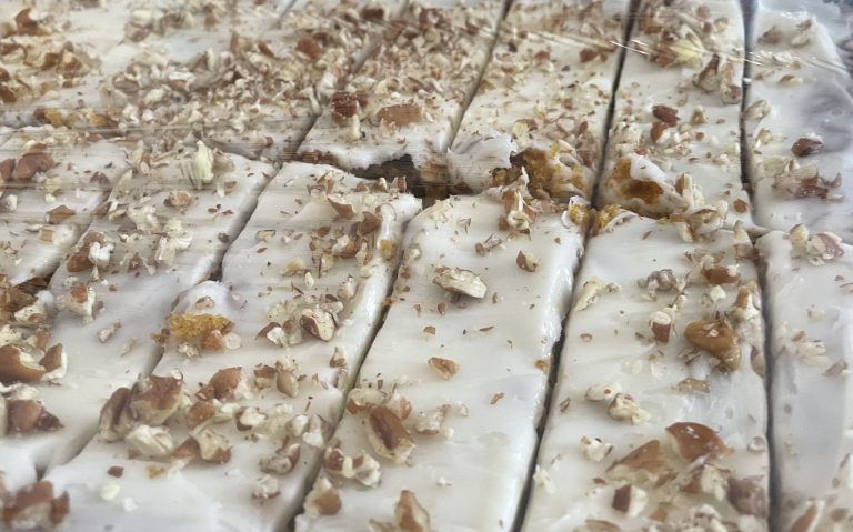Gluten-free carrot cake bars topped with cream cheese frosting on a sheet pan