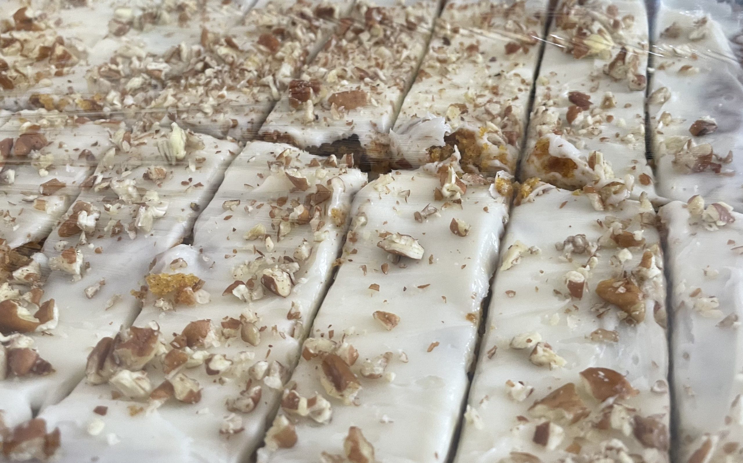 Gluten-free carrot cake bars topped with cream cheese frosting on a sheet pan